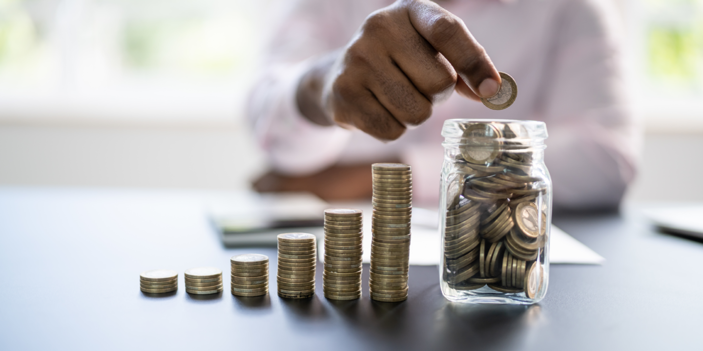 A person counting coins and putting them in a jar