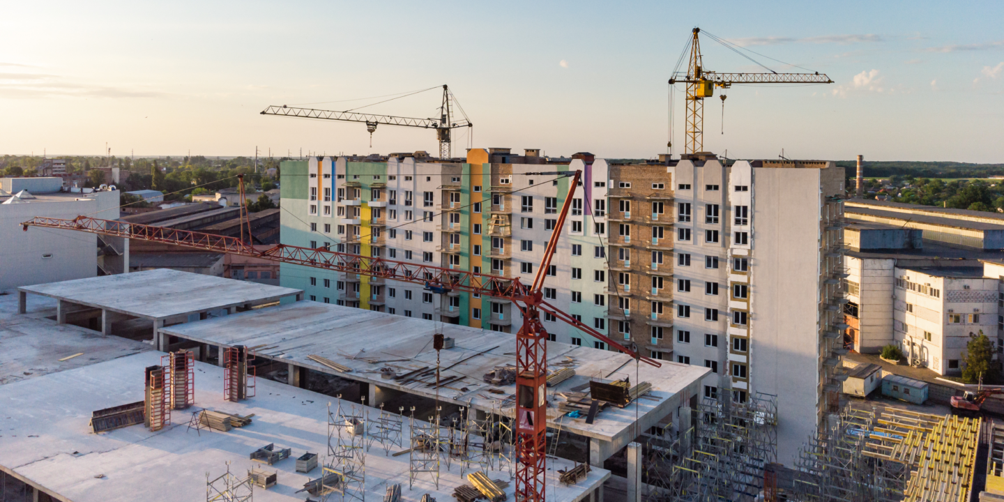 A construction site with cranes and a partially built apartment building.