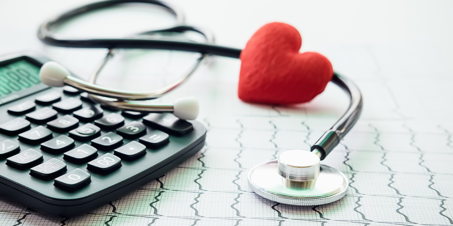 A stethoscope, calculator, and heart symbol arranged on a sheet of paper, representing healthcare and finance integration.