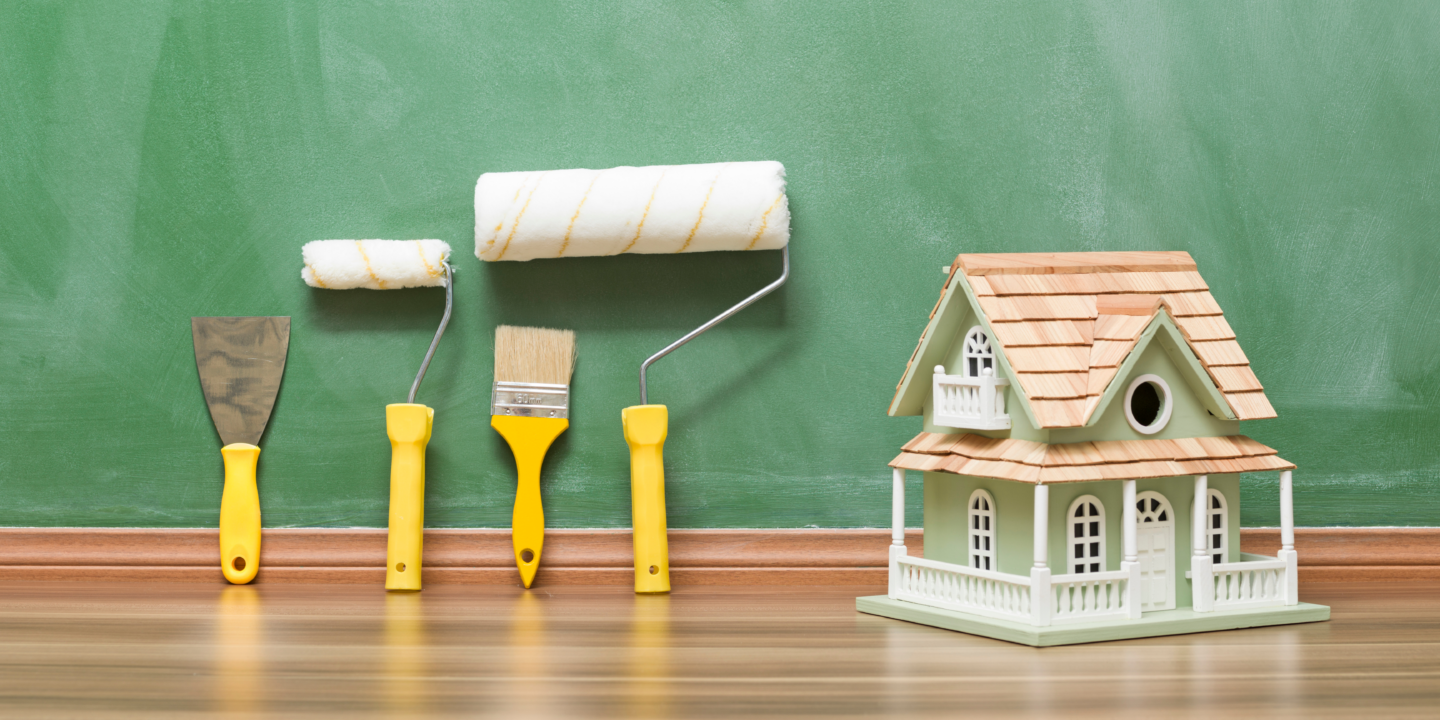 A house illustration with paint rollers and brushes displayed on a green chalkboard background.