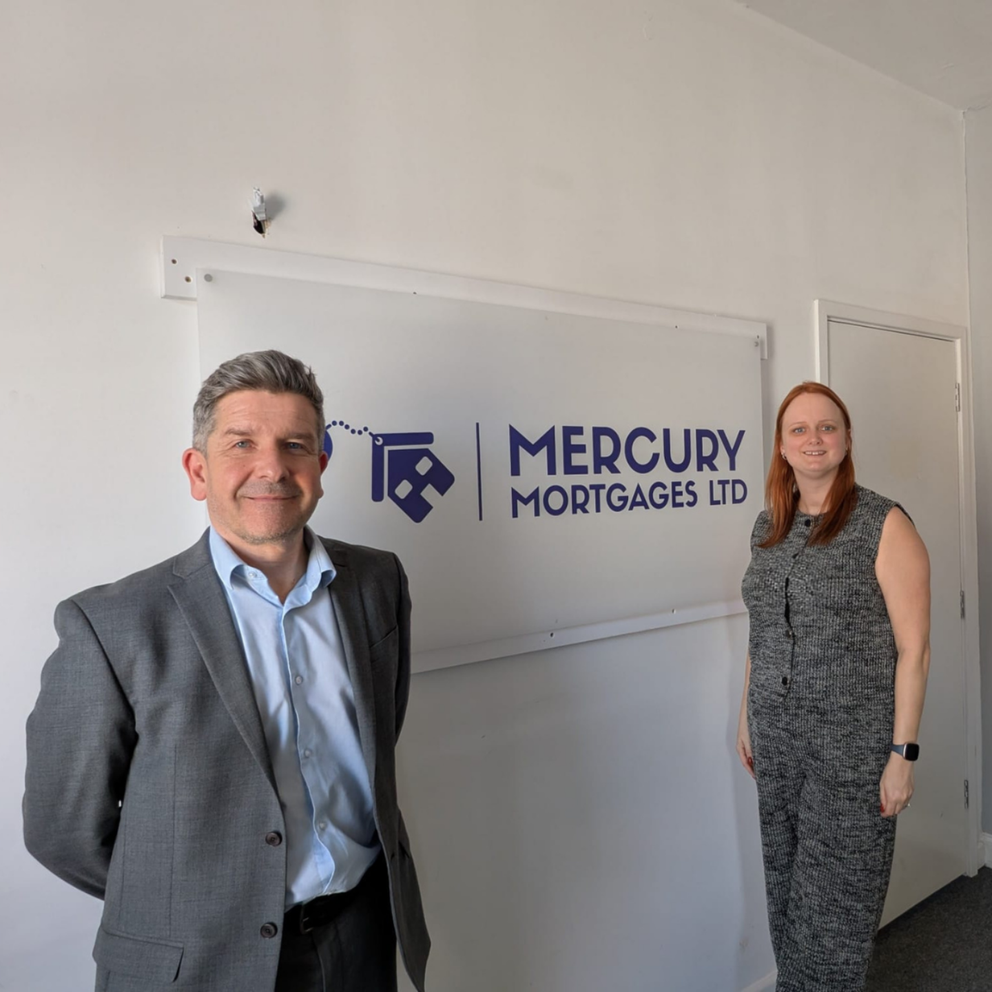 Michelle Strelley of Mercury Mortgages Ltd standing in her office alongside Graeme Lewis, Head of Network Engagement at The Cornerstone Network, in front of her company branding sign.